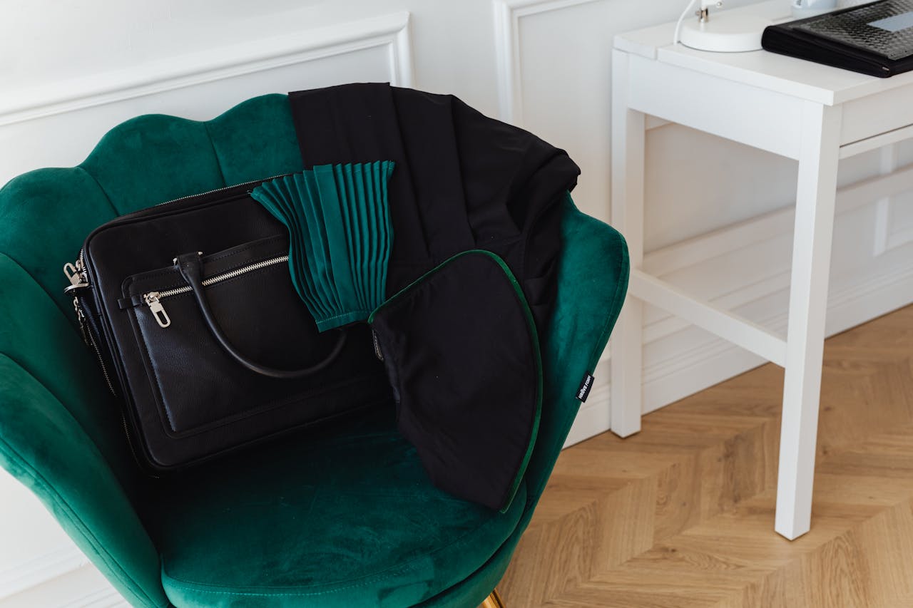 Stylish green accent chair with a black handbag in a minimalist interior setting.
