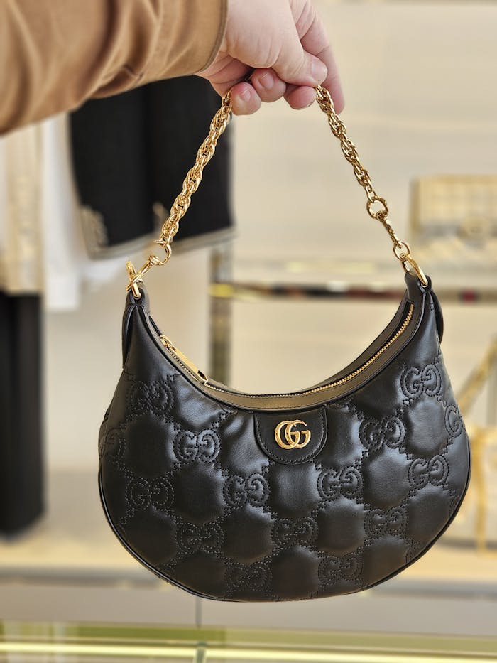 Luxury black handbag with gold accents showcased indoors, emphasizing style and elegance